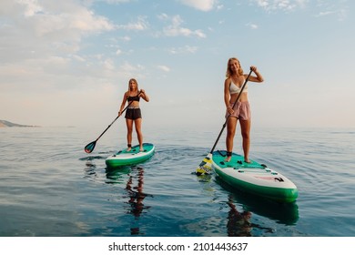 June 25, 2021. Anapa, Russia. Slim girls rowing on stand up paddle board at quiet sea. Woman on Red Paddle SUP board in sea.