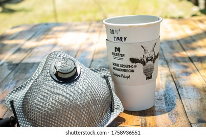 June 6, 2020 - Dripping Springs, Texas - Throw Away Coffee Cup Next To A Mask, On A Wooden Table During The Corona Virus Pandemic. This Picture Shows The Concept Of What The ‘new Normal’ Looks Like.