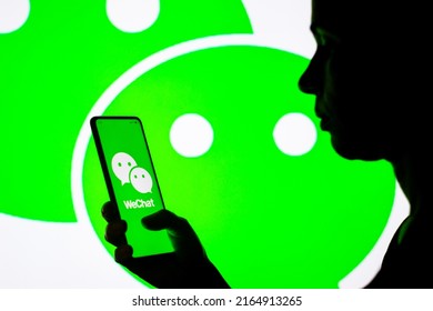June 8, 2022, Brazil. In this photo illustration, a woman's silhouette holds a smartphone with the WeChat logo displayed on the screen and in the background