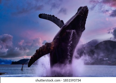 Juneau, Alaska, United States Of America. Statue Of A Big Wale Jumping Out From Water In A Small Touristic Town. Dramatic Sunset Sky