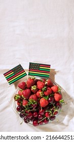 Juneteenth Day Picnic Background With Black Liberation African American Flags, Sweet Salad With Cherries And Strawberries, Strawberry Cheesecake