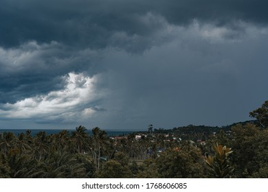 Jungle Village And Sea In The Sunlight Against A Dramatic Stormy Sky And Approaching Rain On A Tropical Island. View From Balcony.