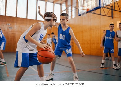 Junior basketball players playing basketball at indoor court and practicing for a game. An active dynamic boys in action playing basketball on training. A young basketball team is practicing game. - Powered by Shutterstock