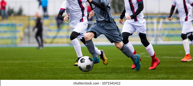 Junior Football Match. Soccer Game For Youth Players. Boys Playing Soccer Match on Football Pitch. Football Stadium and Grassy Field in the Background