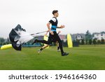 Junior Football Player Running with Parachute. Soccer Endurance and Strength Training. Player Speed Testing. Professional Soccer Strength Test. Young Boy in Football Club Exercise on Training Venue