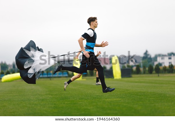 Junior Football Player Running with Parachute.\
Soccer Endurance and Strength Training. Player Speed Testing.\
Professional Soccer Strength Test. Young Boy in Football Club\
Exercise on Training\
Venue