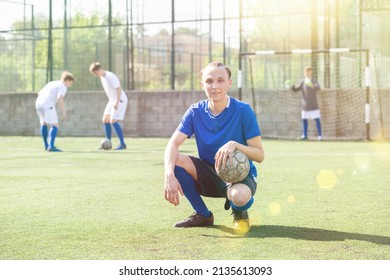 Junior Football Player Sitting On On Field With Ball