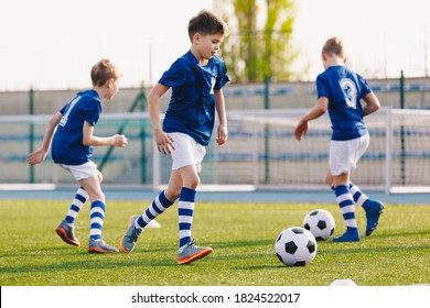 Junior Football Players Making Sports Training, Happy Boys On Soccer Practice Session On Summer Time. School Sports Stadium In The Background