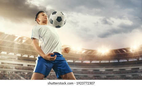 Junior Football Or Soccer Player At Stadium In Flashlight. Young Male Sportive Model Training. Moment Of Attacking, Catching. Concept Of Sport, Competition, Winning, Action, Motion, Overcoming.