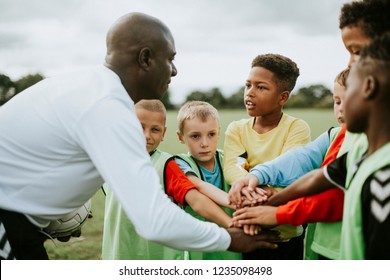 Junior football team stacking hands before a match - Shutterstock ID 1235098498