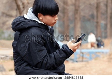 Junior high school boy looking at smartphone Asian Japanese                               