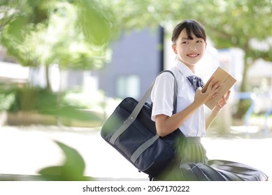 Junior high school student sitting on a park bench and reading - Shutterstock ID 2067170222