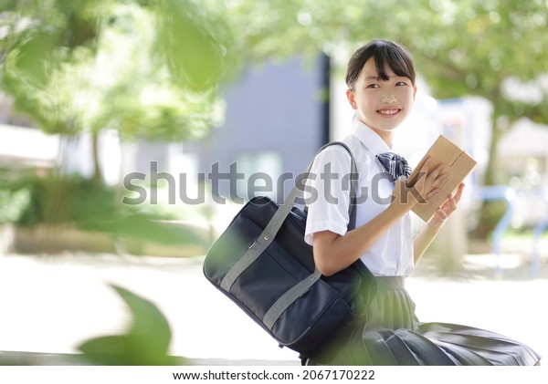 Junior high school student sitting on a park\
bench and reading