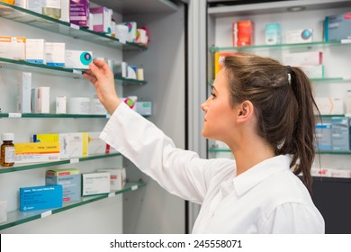 Junior Pharmacist Taking Medicine From Shelf At The Hospital Pharmacy