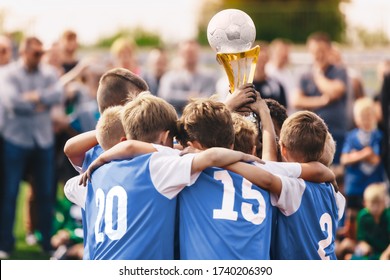 Junior Sport - Celebration. Boys In Sports Soccer Team Rising Up Golden Cup. Young Male Triumphant Footballers. Happy Kids Enjoying Winning In Tournament