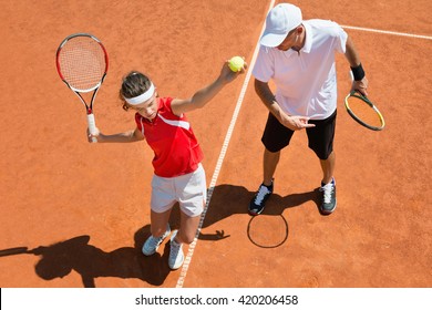 Junior Tennis Player Practicing Service With Tennis Coach