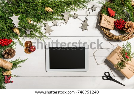 Juniper branches with a Christmas decor. Christmas, New Year background. Coniferous branches of juniper and white tablet with black screen. Top view, flat design.