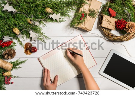 Juniper branches with a Christmas decor. Christmas, New Year background. Coniferous branches of juniper, notepad and white tablet with black screen. Top view, flat design.