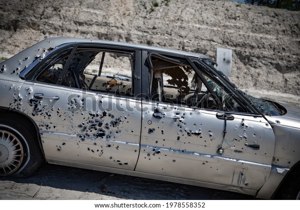 Junk cars\
with bullet holes and  bullets\
inside.