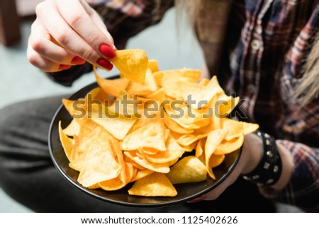 junk fast food and unhealthy nutrition. woman eating chips from a bowl of crunchy crisps