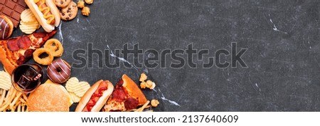 Junk food corner border over a dark banner background. Collection of take out and fast foods. Pizza, hamburgers, french fries, chips, hot dogs, sweets. Overhead view with copy space.