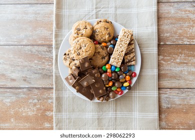 Junk Food, Sweets And Unhealthy Eating Concept - Close Up Of Candies, Chocolate, Muesli And Cookies On Plate