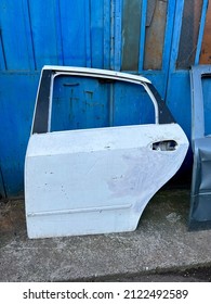 Junk Yard, Damaged Old Car Doors Leaning On Wall At Entrance Of Dent Repair Technician Service For Vehicles. Repair And Remove Dents On Body And Prepare Surface For Spray Painting In Car Service