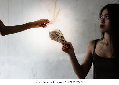 A Junkie Girl Is Giving Dollars Money To A Drug Dealer For Buying Heroin, Cocaine Or Narcotic At Slums House. The Narcotic Is So Expensive. A Drug Addict Young Girl Looks Thin And Illness