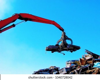 Junkyard crane with claw moving crushed car - Powered by Shutterstock