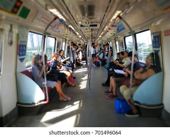 Jurong East MRT, Singapore - August 23, 2017: People Sitting In Train And Some Of Them Sleep Or Play Hand Phone To Kill The Time With A Bit Blurred Background.