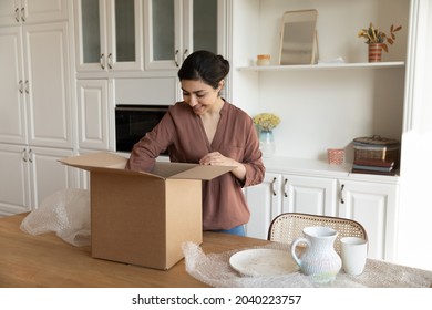 Just after relocation. Happy biracial woman unpack stuff take ceramic tableware out of big carton container at modern kitchen. Young indian lady get internet purchase open box with newly bought dishes - Powered by Shutterstock