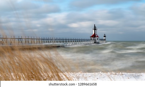 Just after a winter snow storm blanketed the land the waters of lake Michigan were rough because of the wind and standing steady and true is the north pier lighthouse of St. Joseph Michigan - Powered by Shutterstock