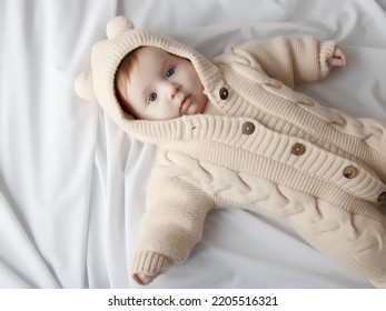 Just Beautiful. Cute Smiling Baby. Cute 3 Month Old Baby Girl Infant On A Bed On Her Belly With Head Up Looking With Her Big Eyes. Warm, Fluffy Biege Clothes. Closeup. Three Months Old Baby