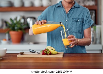 Just give me juice and Im good. Shot of an unrecognisable woman pouring orange juice while preparing breakfast in the kitchen at home. - Powered by Shutterstock