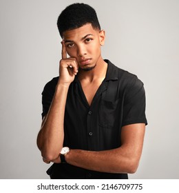 Just Give Me A Minute To Think. Portrait Of A Handsome Young Man Posing Against A Grey Background Inside Of A Studio.