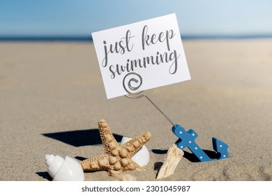 JUST KEEP SWIMMING text paper greeting card in anchor paper holder   starfish seashell summer vacation decor  Sandy beach sun coast  Holiday concept postcard  Getting away Travel