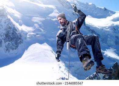 Just a little further.... Shot of a mountaineer hanging from a rope on a rockface.