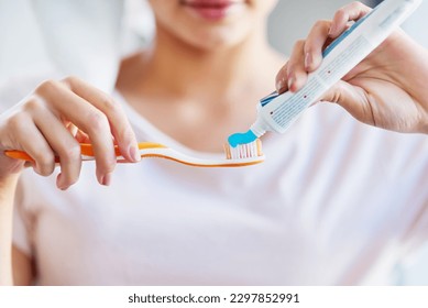 Just a little goes a long way. Closeup shot of a young woman squeezing toothpaste onto her toothbrush in the bathroom at home.