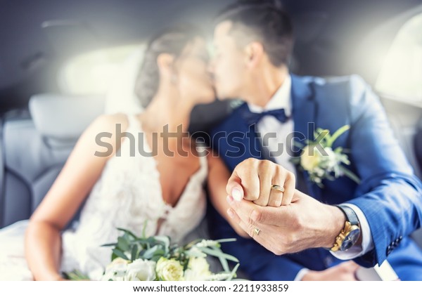 Just married couple kisses in the car showing\
rings on fingers towards the\
camera.