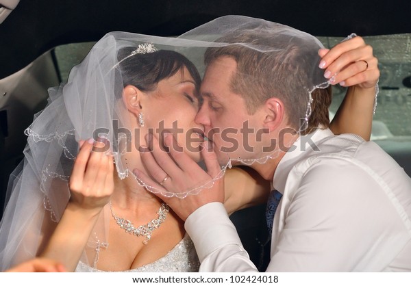 just
married couple is kissing in car under bridal
veil
