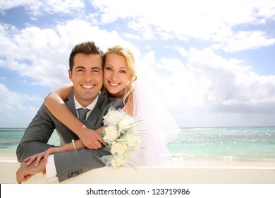Just married couple leaning on fence by the beach
