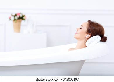 Just relax. Content beautiful young woman listening to music and closing her eyes while taking a bath