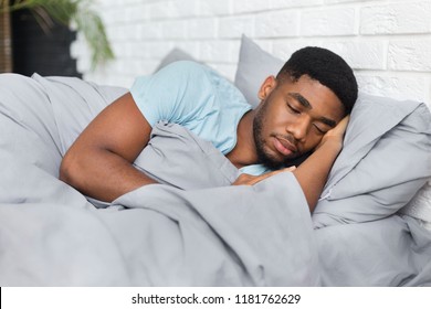 Just resting. Young african-american man sleeping in bed at home, having good dreams, copy space