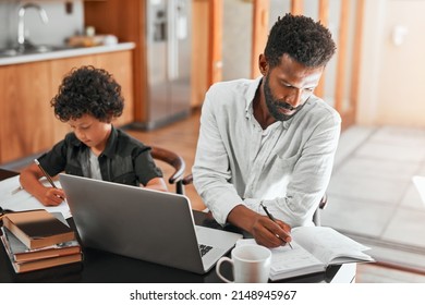 Just A Single Dad Working From Home. Shot Of A Man Using His Laptop While Sitting With His Son.