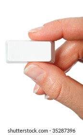 Just a small empty rectangular key from a computerkeyboard between fingers vertical, white background