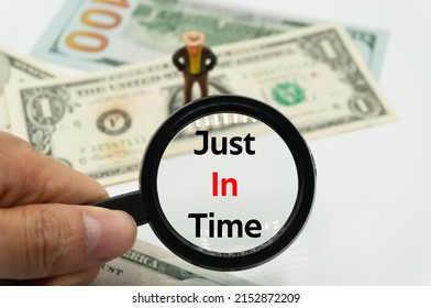 Just In Time.Magnifying glass showing the words.Background of banknotes and coins.basic concepts of finance.Business theme.Financial terms.