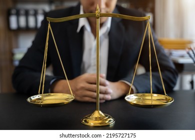 Justice And Law Concept. Close Up Golden Scales With Blurry Lawyer As Background.