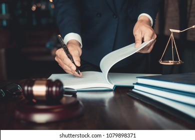 Justice And Law Concept. Gavel On Sounding Block In Hand's Male Judge At A Courtroom, Working With Document Law Books, Report The Case On Table In Modern Office.
