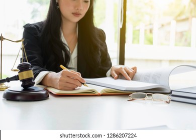 Justice and law concept. Gavel on sounding block in hand's Male judge at a courtroom, working with document law books, report the case on table in modern office.