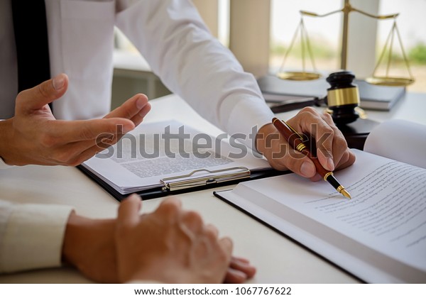 Justice and Law concept. Legal
counsel presents to the client a signed contract with gavel and
legal law or legal having team meeting at law firm in
background